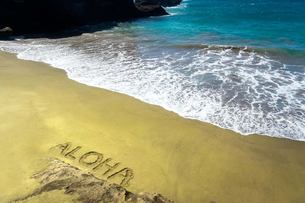 View of Papakoleaâ green sand beach on the Big Island with the word Aloha written in the sand.