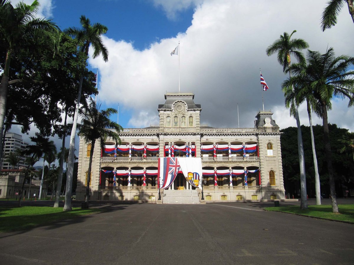 View of Iolani Palace in downtown Honolulu decorated with Hawaiian flags.