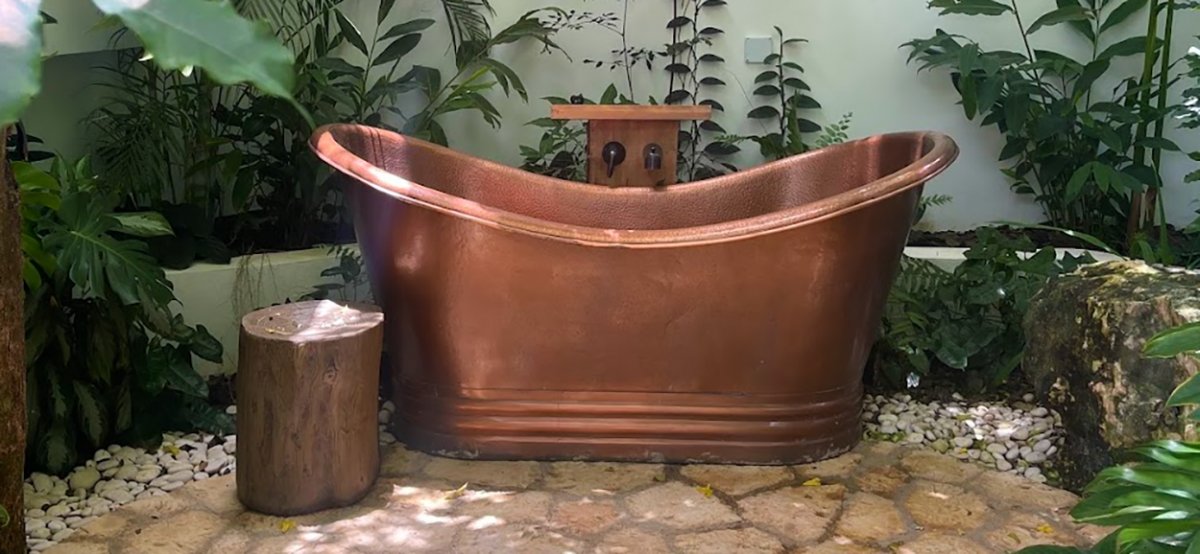 Beautiful view of outdoor brass bathtub at Rose Hall & Half Moon Bay, Jamaica.