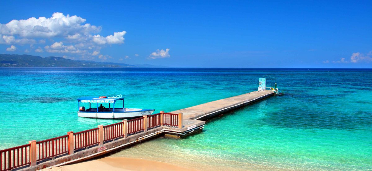 View of blue waters with boat off beach dock at Doctor's Cave Beach in Montego Bay, Jamaica.