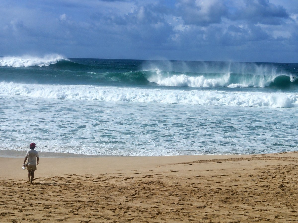 View of woman walking towards water at Banzai Pipeline north shore Oahu