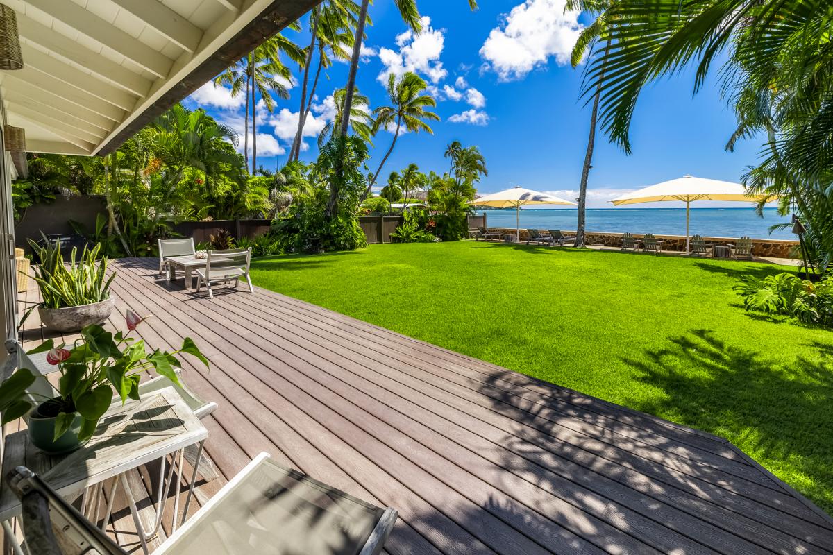 Spacious lanai opening onto a lush green lawn with ocean views.