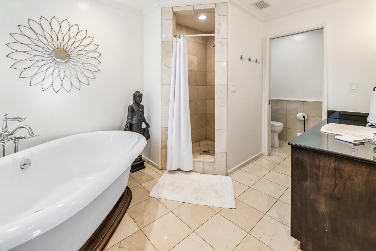 Elegant ensuite for Primary Bedroom 2 with a soaking tub, walk-in shower, and double vanity.