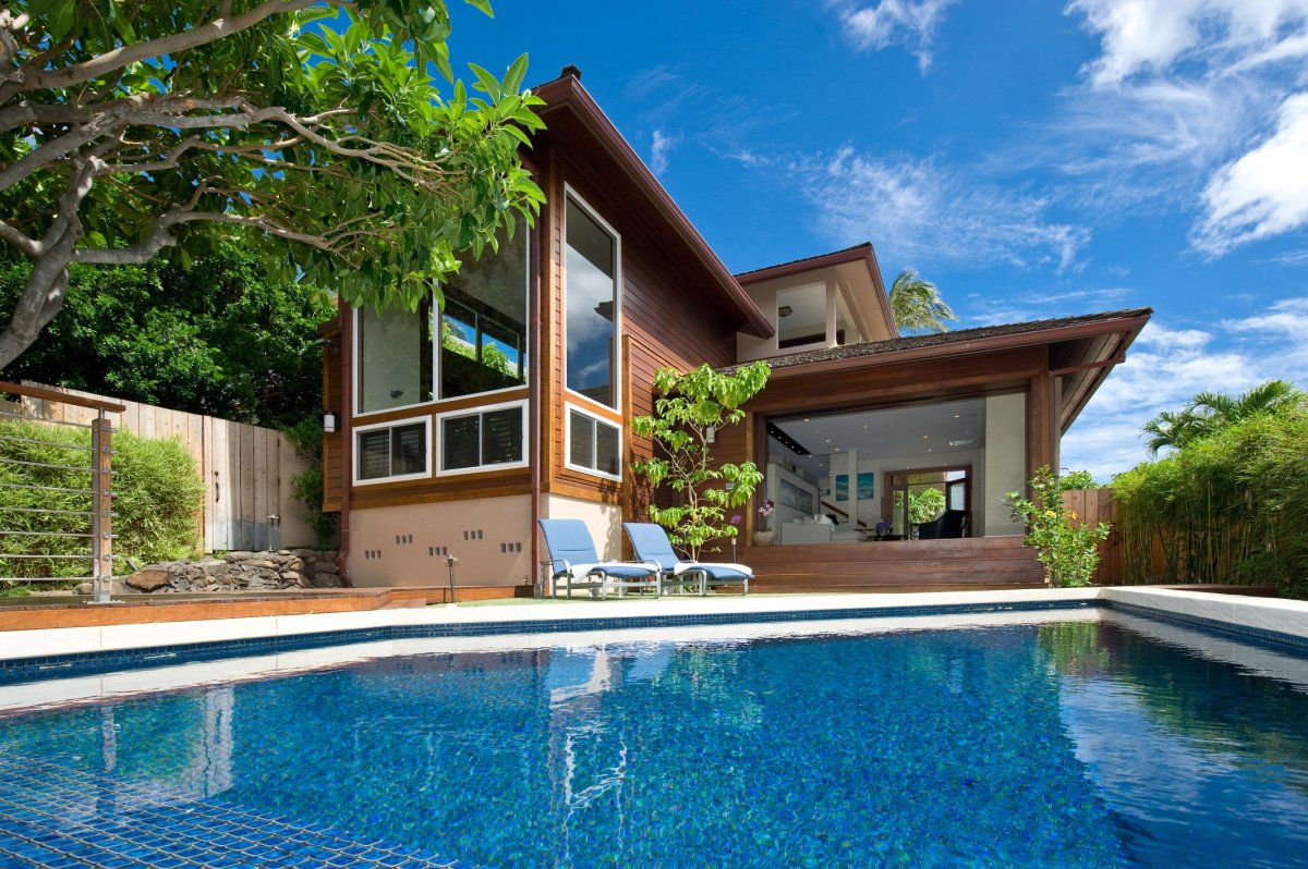 View of Casa de Makalei Villa with a swimming pool, patio chairs, and a lounge chair next to the pool