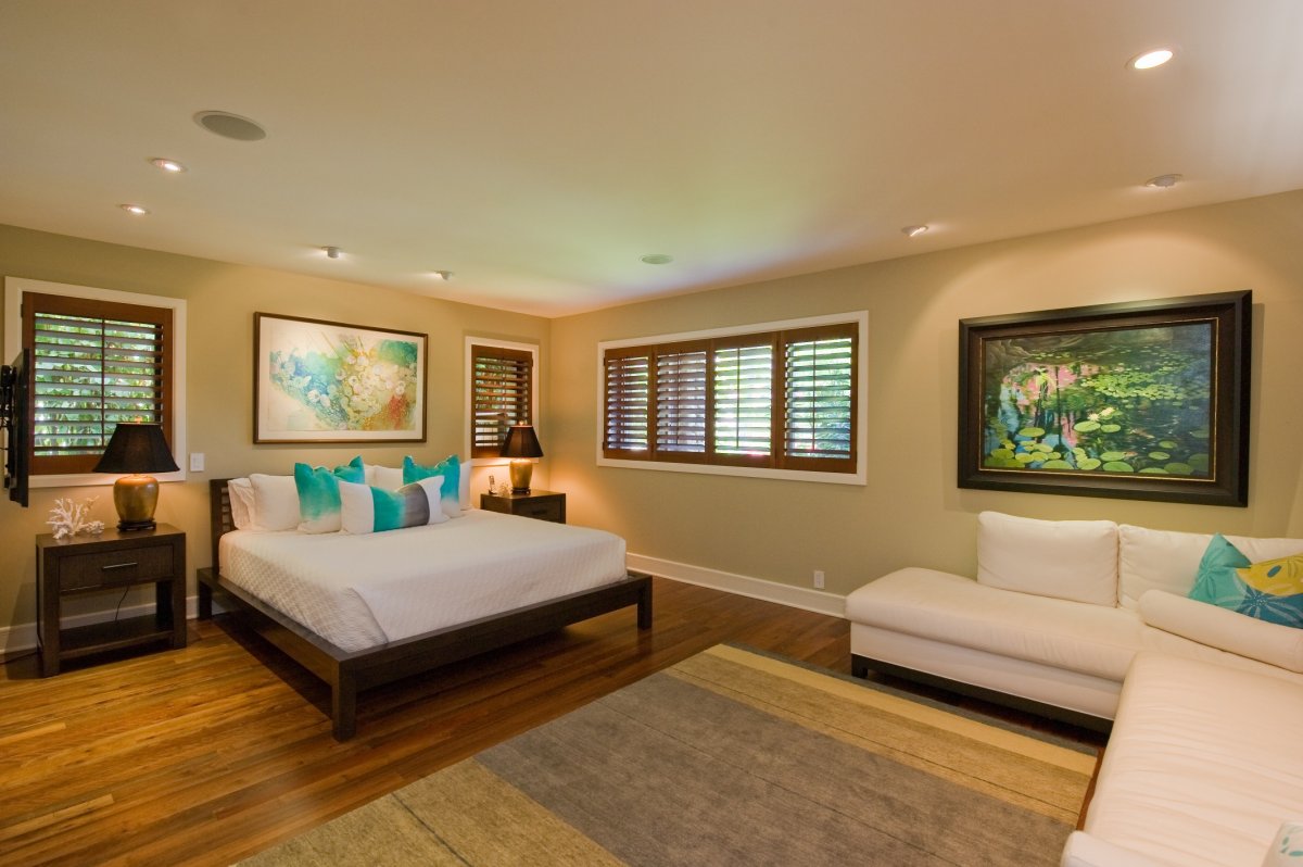 Bedroom with king-size bed, two nightstands with lamps on top, an L-shaped sofa, and a Flat-Screen TV