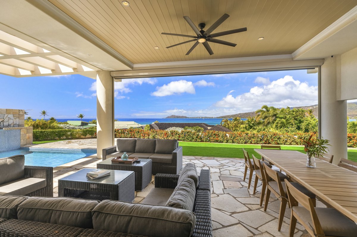 Hale Makana's spacious outdoor living area with a ceiling fan, a large dining table, and chairs