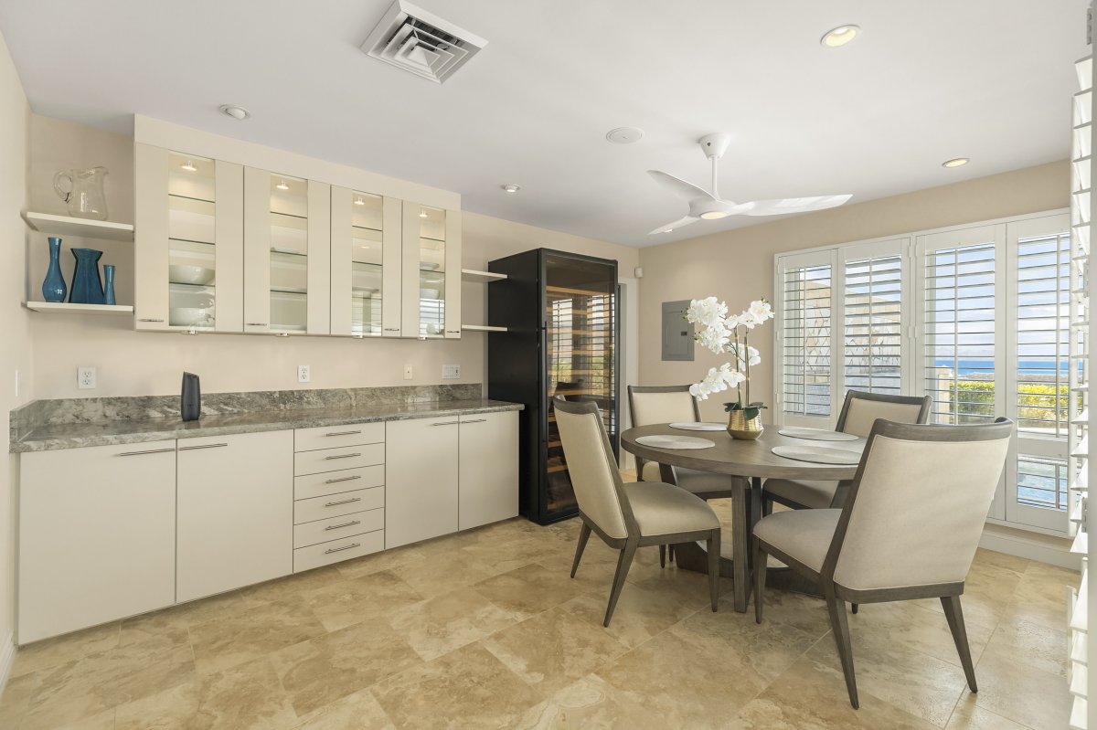 Hale Makana's dining area with a round table and four upholstered chairs, a ceiling fan, shaker-style cabinets, and a wine cooler