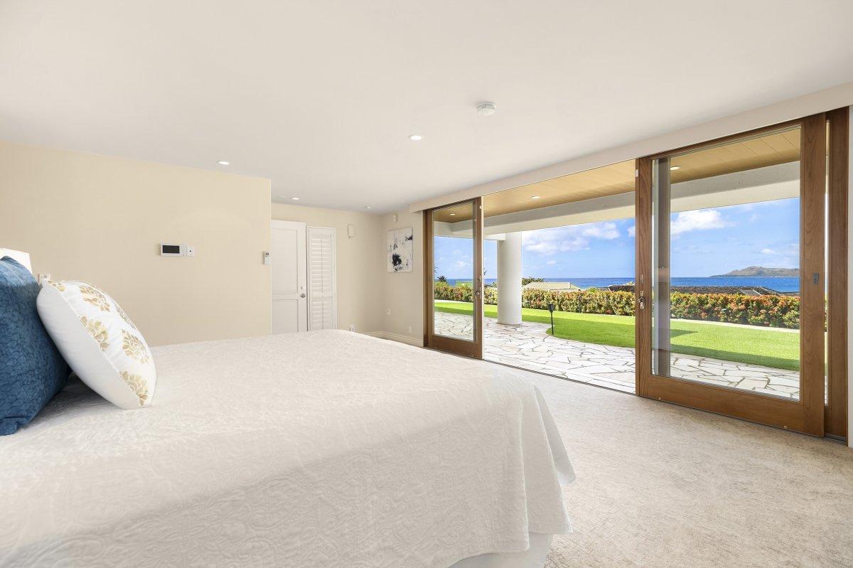 Hale Makana's Primary Bedroom with King Bed and a sliding door opening up to the lawn yard