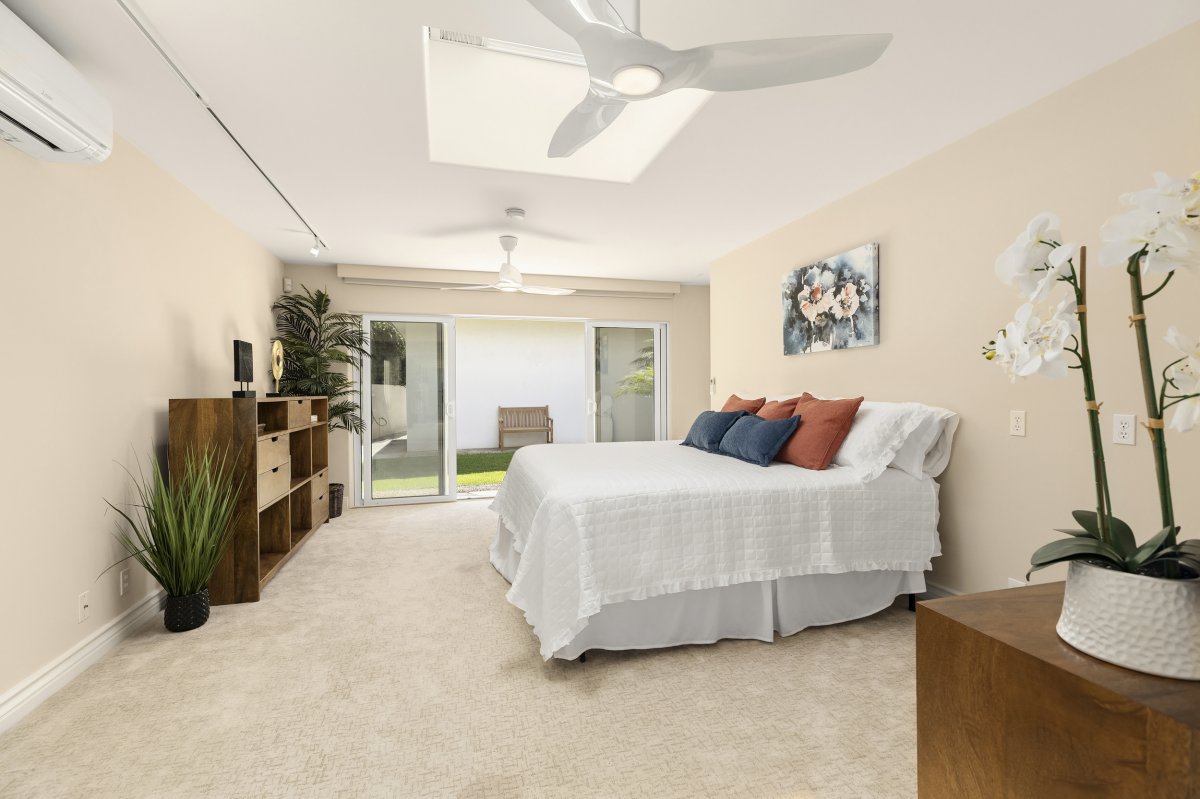 Hale Makana's Bedroom Five with a queen bed, 2 ceiling fans, split air-conditioning, and a sliding door leading up to the lawn yard