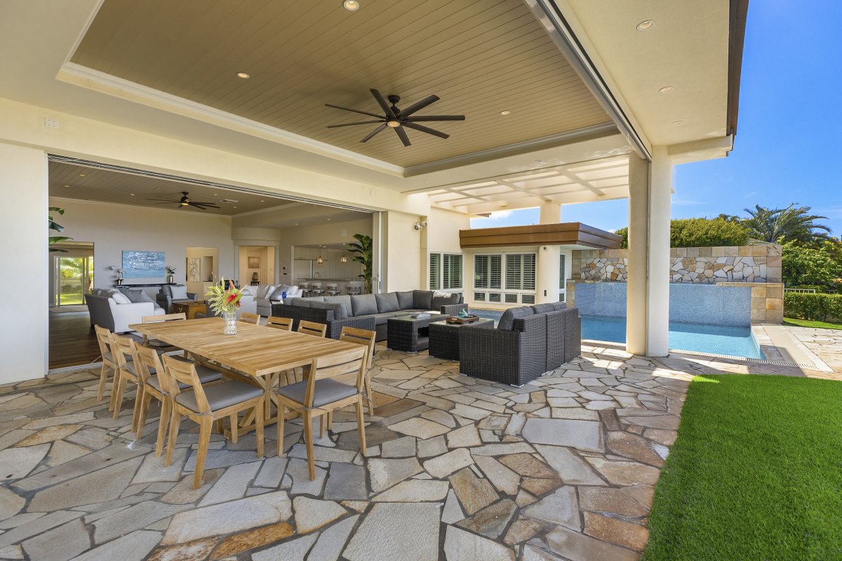 Hale Makana's outdoor space with a covered lanai,  inground pool, manicured front lawn and ocean views