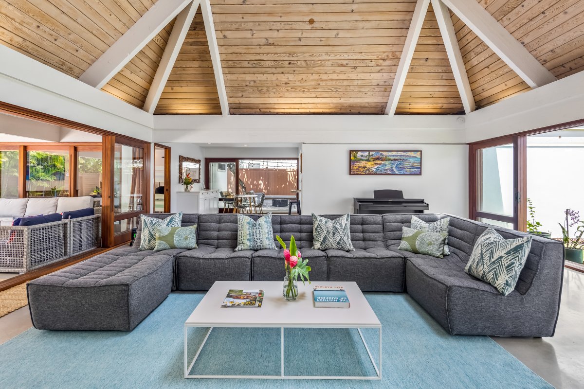 Experience the grandeur of a cathedral ceiling in the living area, complemented by a section of glass roofing, allowing an abundance of natural light to cascade in, illuminating the space beautifully.