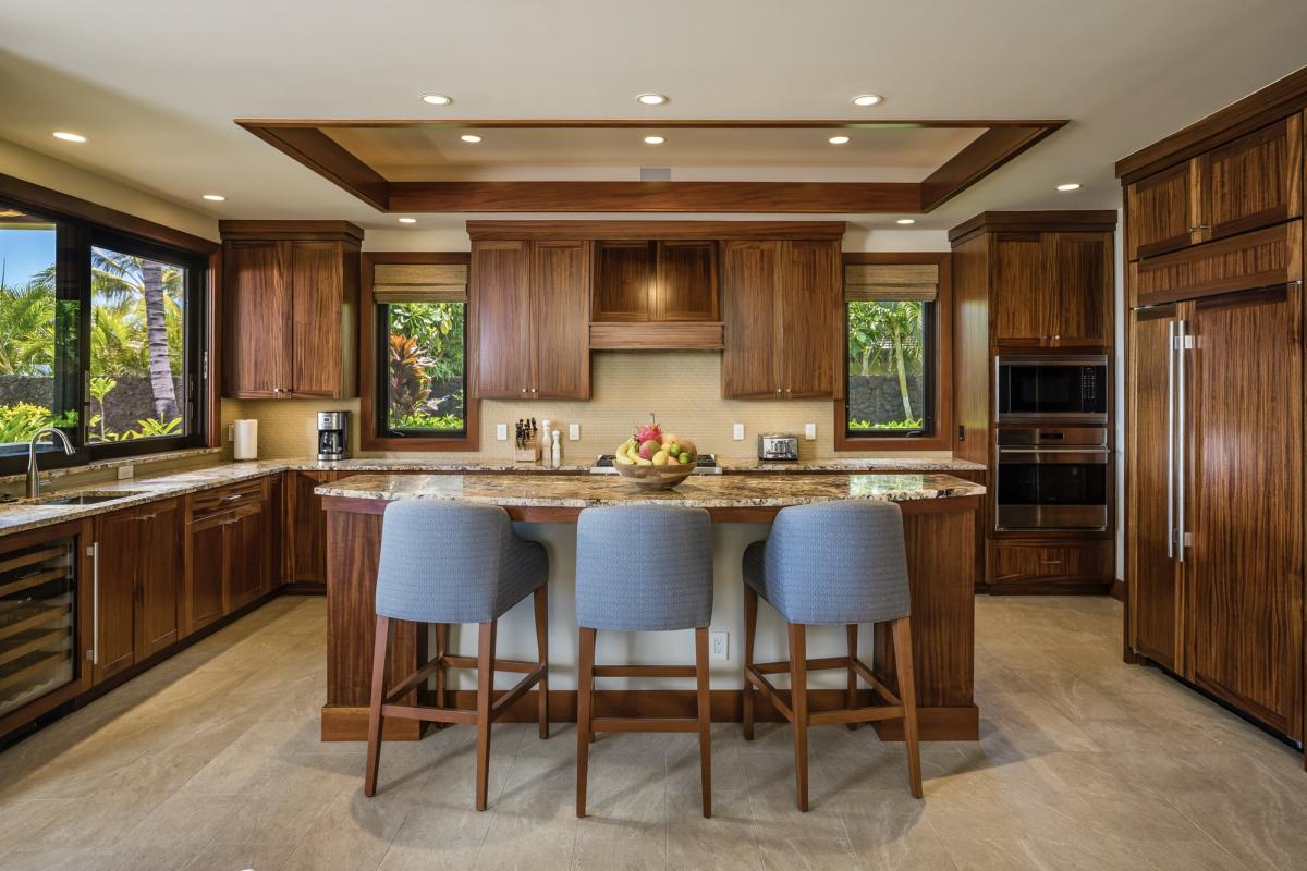 Spacious kitchen with bar seating, rich African mahogany cabinetry, and elegant recessed lighting.