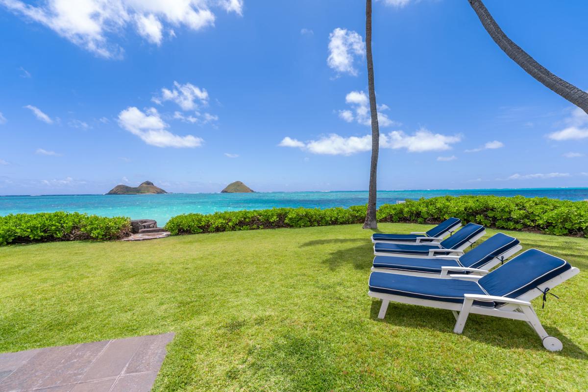 Relax on spacious beachfront grounds with direct access to stunning turquoise waters. Lounge chairs and palm trees frame your private slice of paradise.