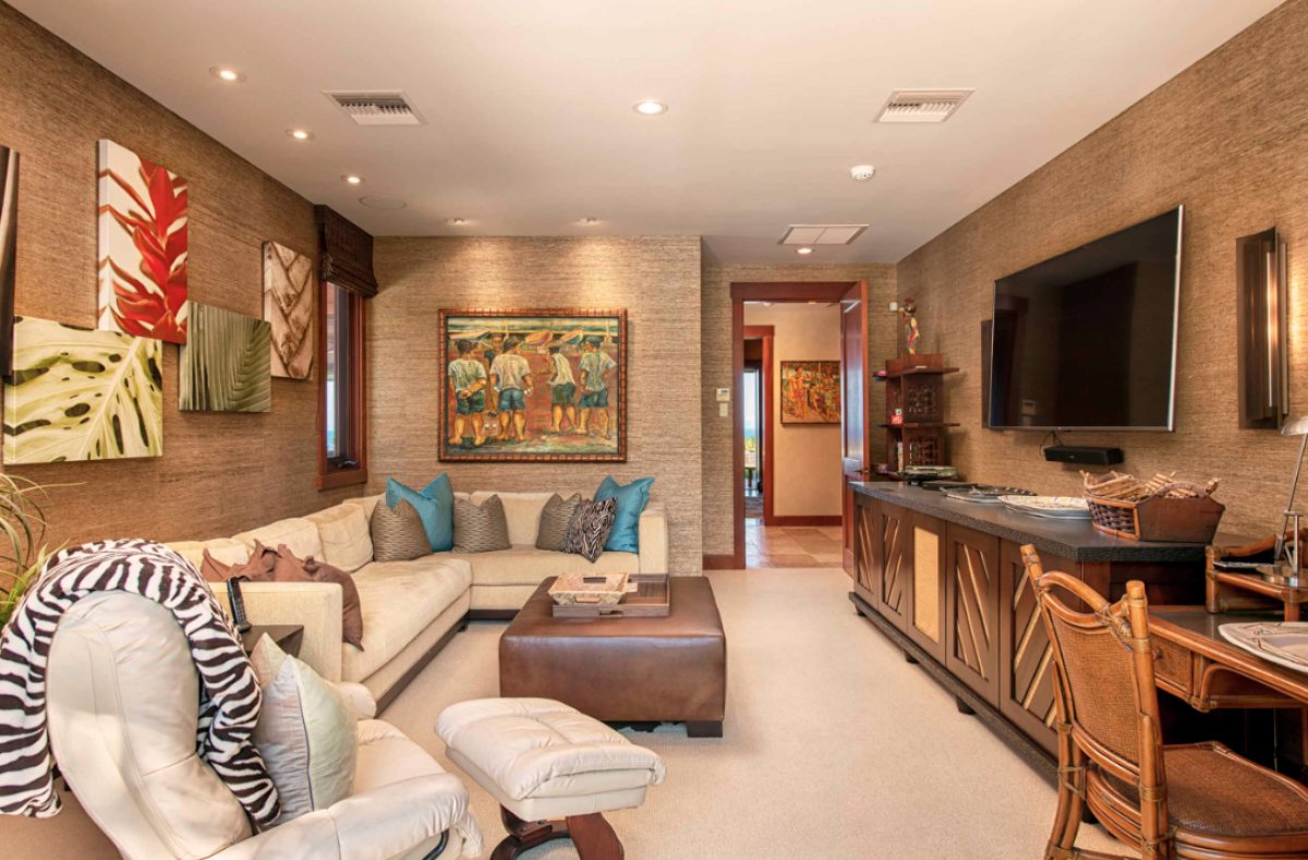 Hale Lani's living room with a comfortable sectional sofa, a flat-screen TV and a small desk with a chair, perfect for working or studying