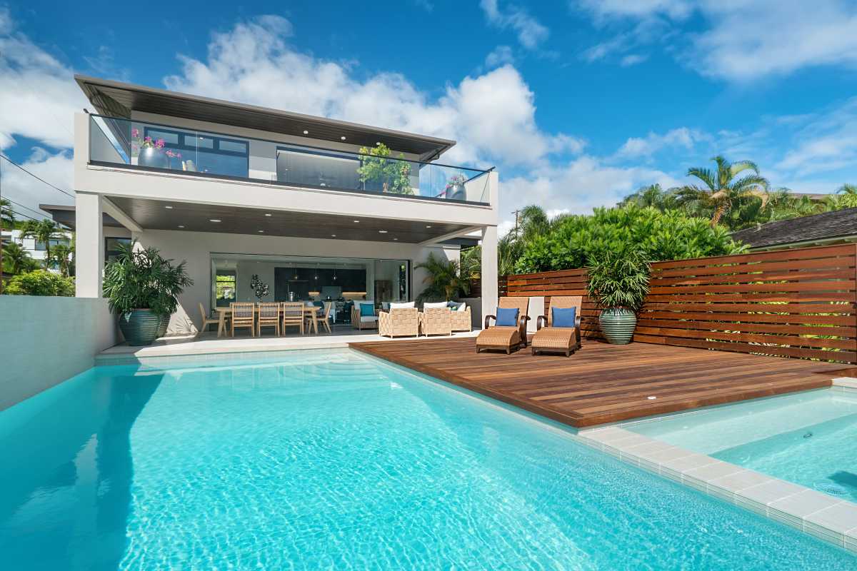 View of Diamond Head Grandeur Villa on Oahu with swimming pool, covered lanai, patio chairs, table and lounge chair next to the pool