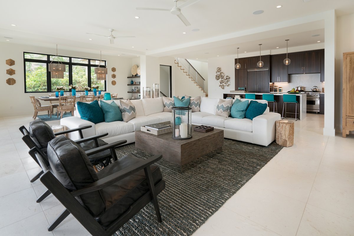 Large living room with a white sectional couch, center table, and two armchairs. Next to it is the dining area and kitchen