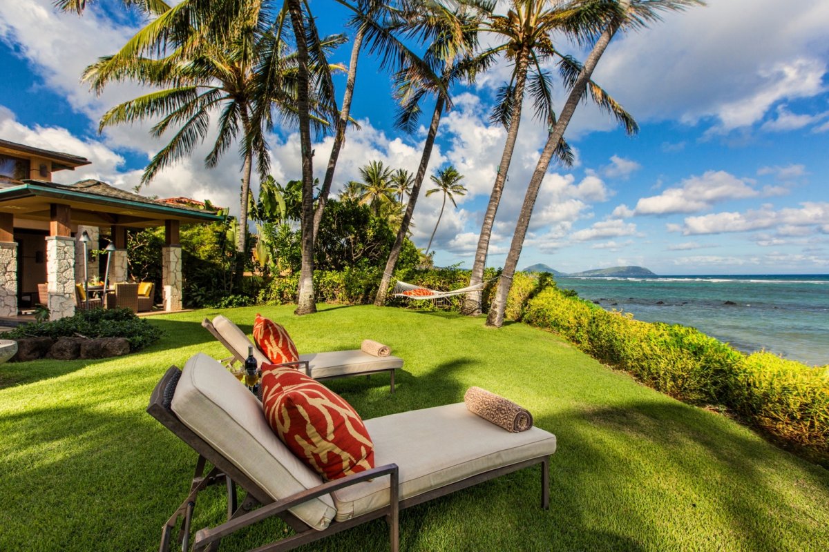 Banyan House beachfront lawn with Cushioned Chaise Lounges, hammock, and crystal clear ocean view