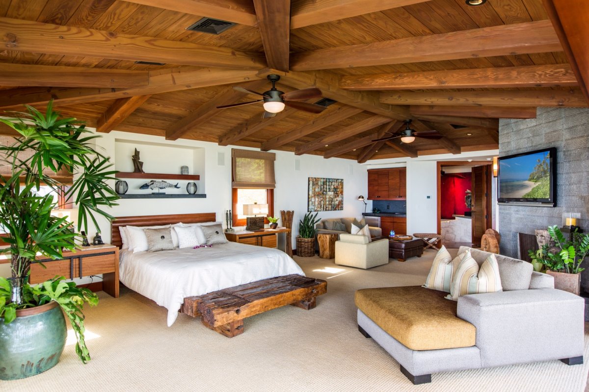 Primary bedroom with sitting areas, LCD TV, and exposed wooden ceiling beams