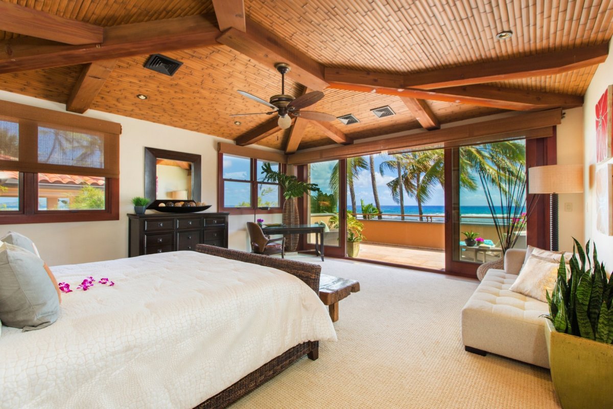 Bedroom with direct access to the terrace, ocean view, ceiling fan, mirror, sitting area, and exposed wooden ceiling beams