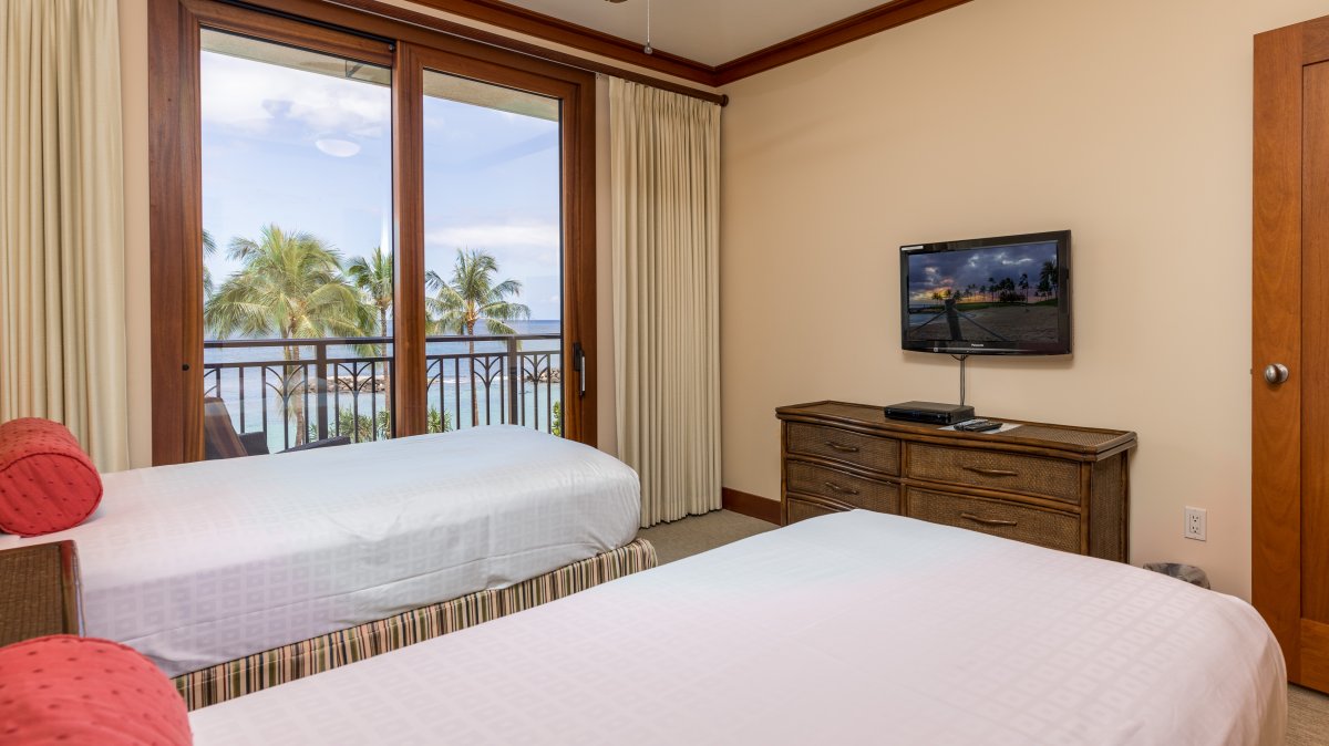 The spacious second guest bedroom with TV and a dresser.