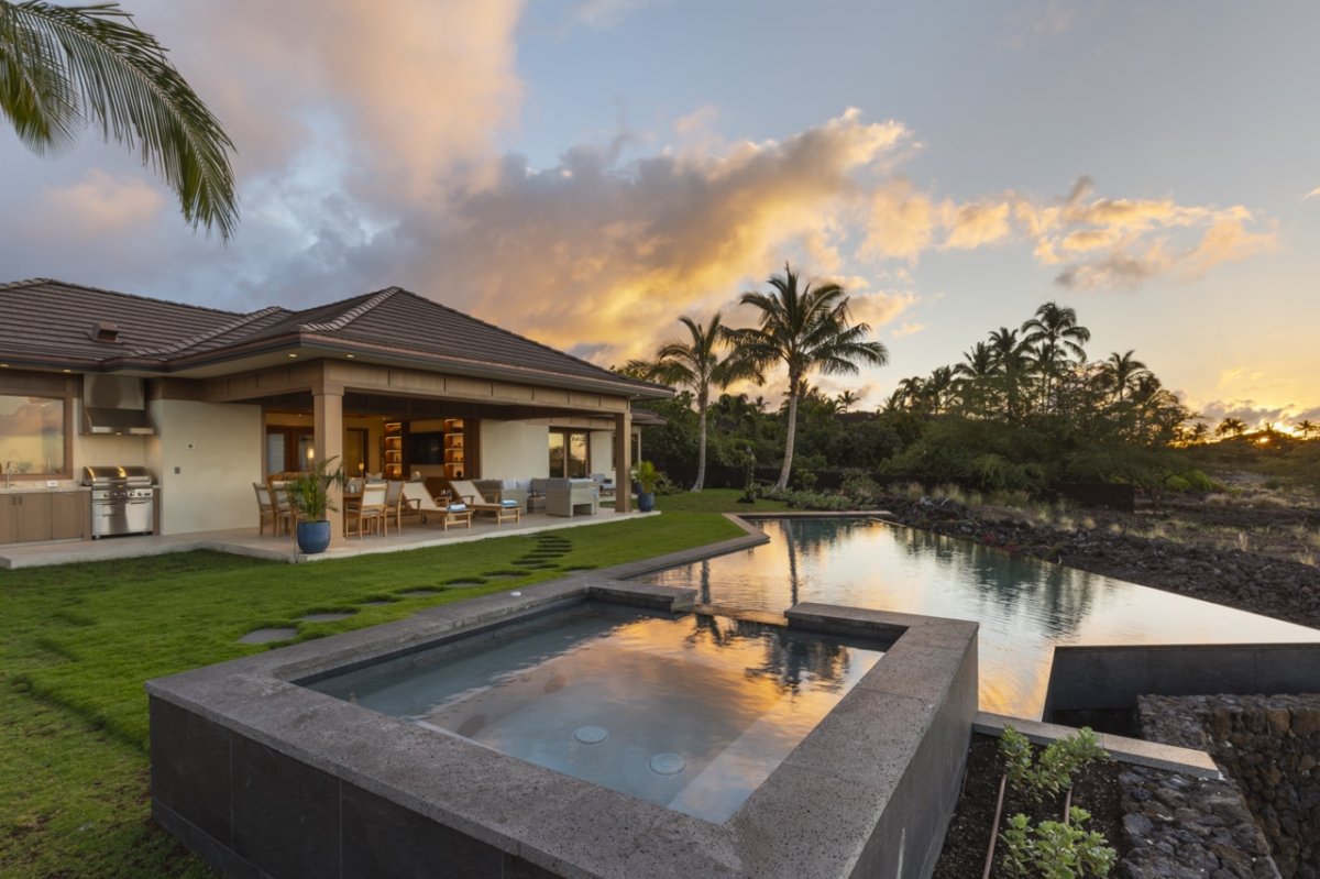 Twilight by the poolside area featuring the custom outdoor kitchen area.