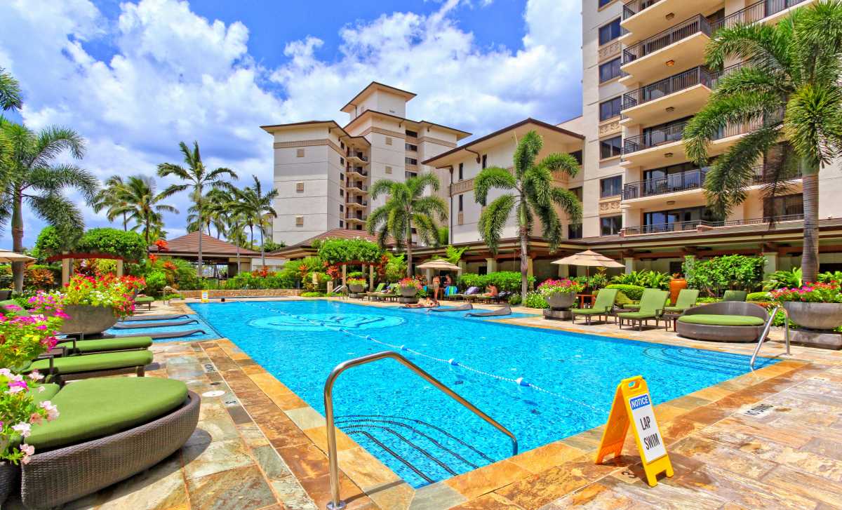 The lap pool with lounge chairs, and table umbrellas.