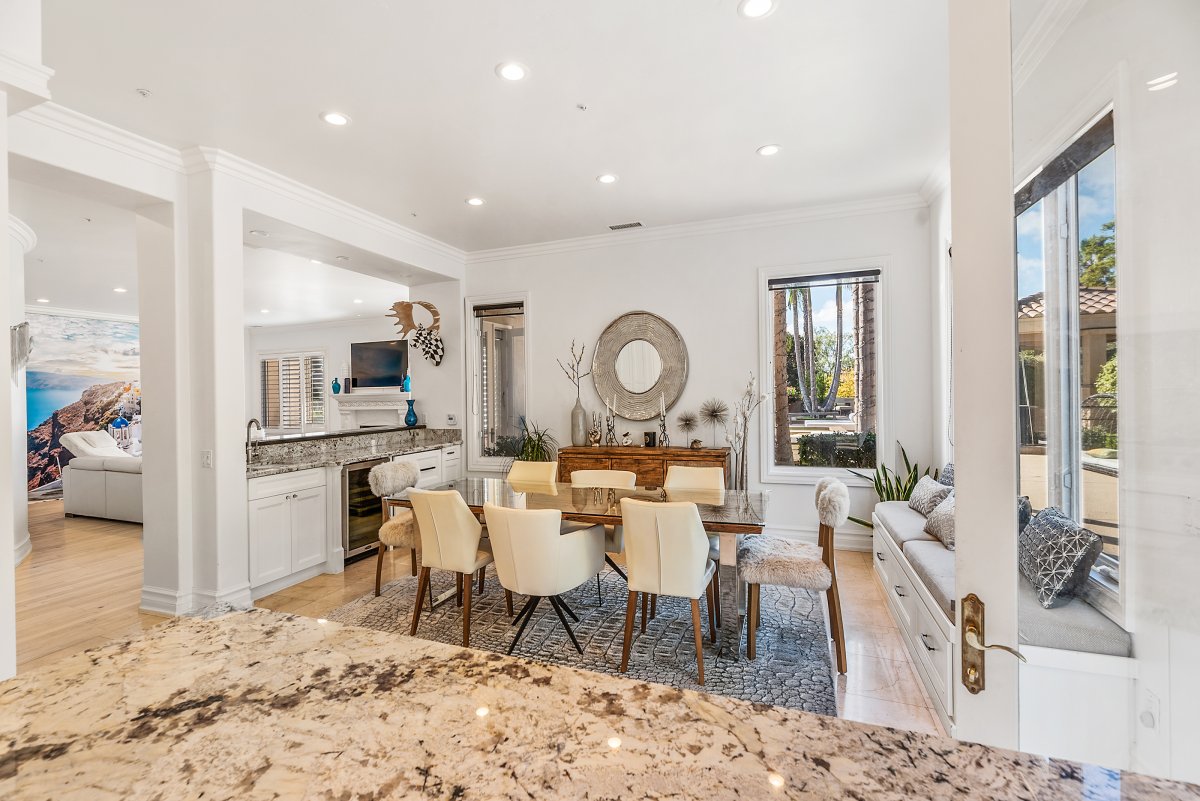 The kitchen area with lots of light, the kitchen is open to an informal dining area, breakfast bar with seating, and French doors to the outdoor kitchen and pool area.