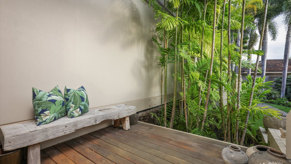 Peaceful, lanai facing the front entry with a bamboo backdrop and island-inspired bench.
