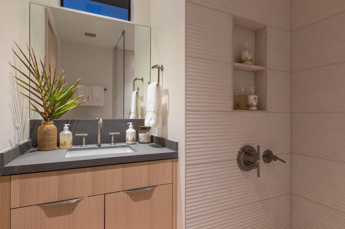 This elegantly designed bathroom features a modern vanity with a sleek wooden base and a sophisticated countertop.