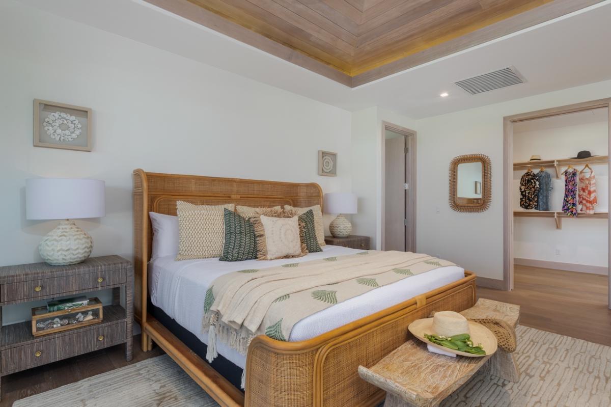 Primary Suite Bedroom 1 (Upstairs): This inviting bedroom features a richly crafted rattan bed frame that adds a touch of natural elegance to the space, complemented by soft, layered bedding that invites relaxation.