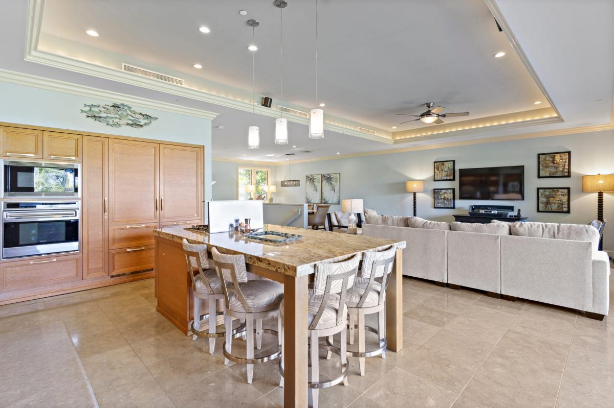 Open kitchen with a granite island and bar seating, flowing into a spacious living area with comfortable seating and modern decor