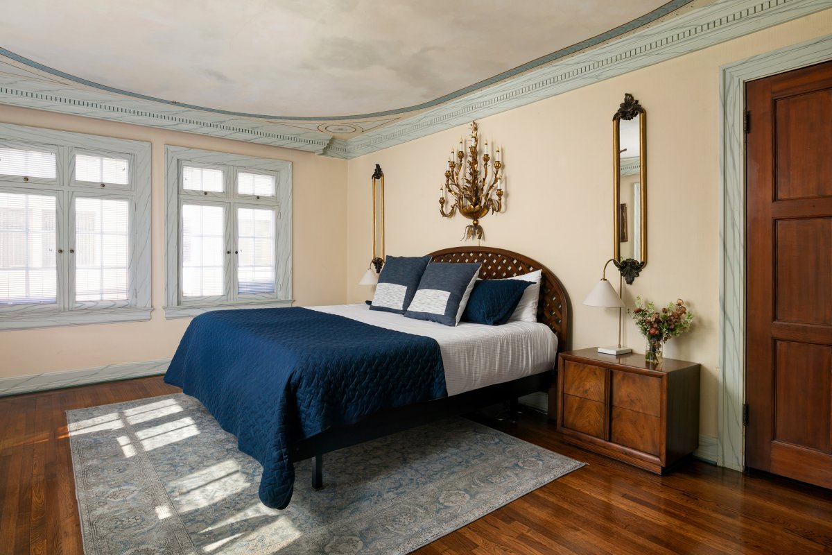 Primary suite with plush bed and airy windows.