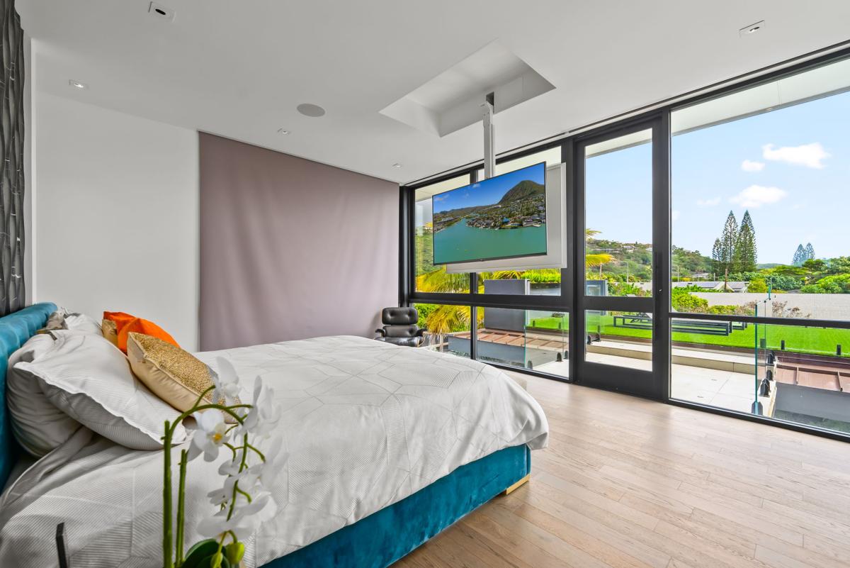 Wake to palm-fringed horizon views in this breezy guest bedroom with floor-to-ceiling windows and seamless outdoor access.