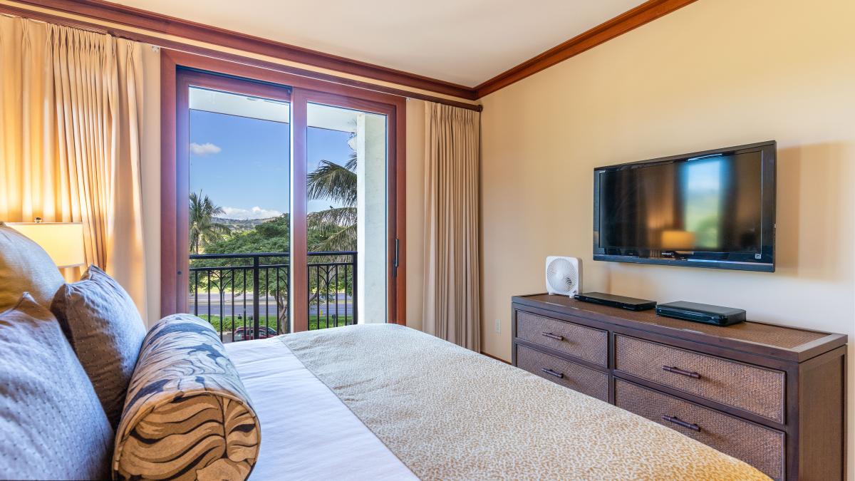 Primary suite with storage, a TV, and lanai access for fresh ocean air.