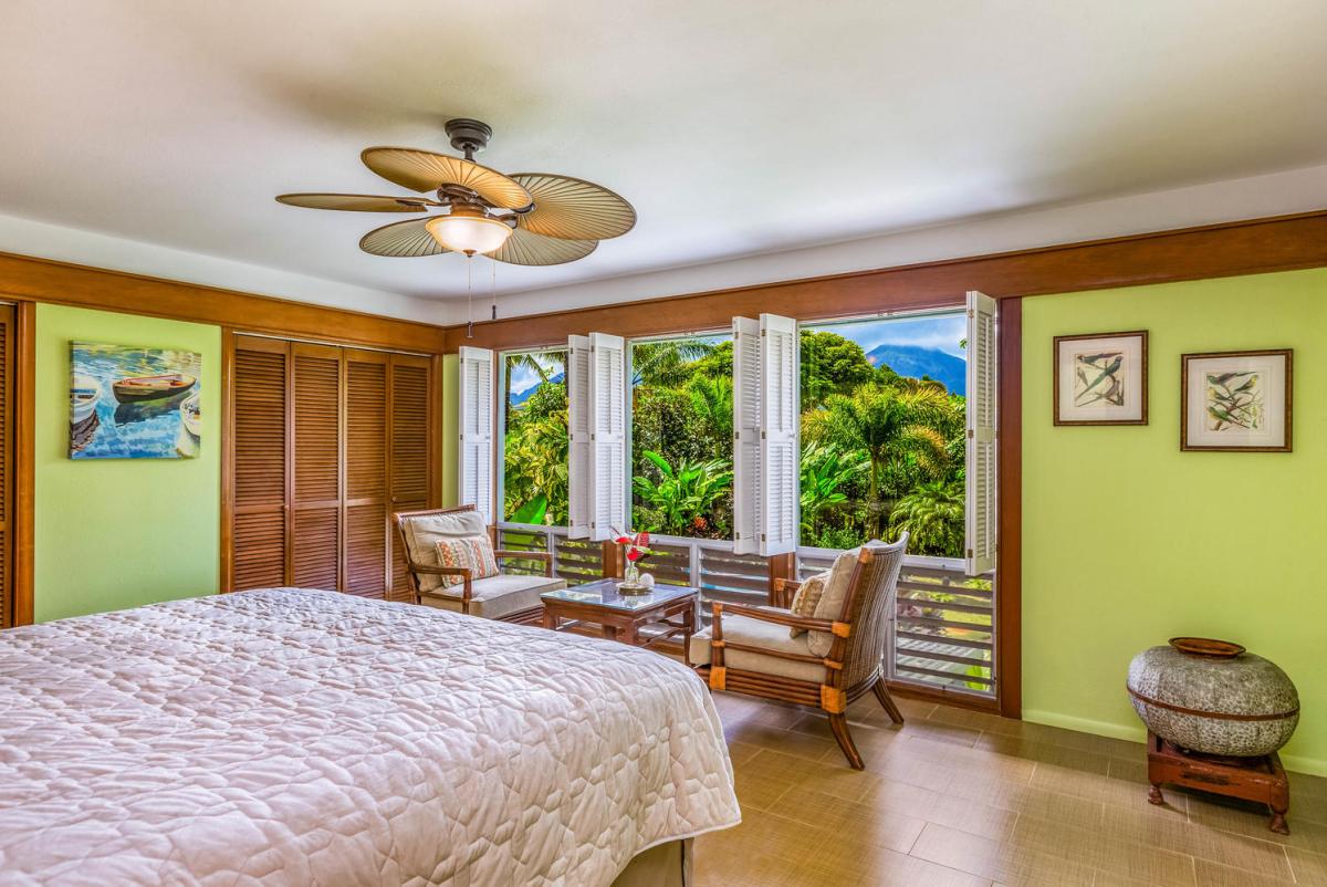 Retreat to the upstairs primary suite with a plush king bed and sweeping views of lush greenery.