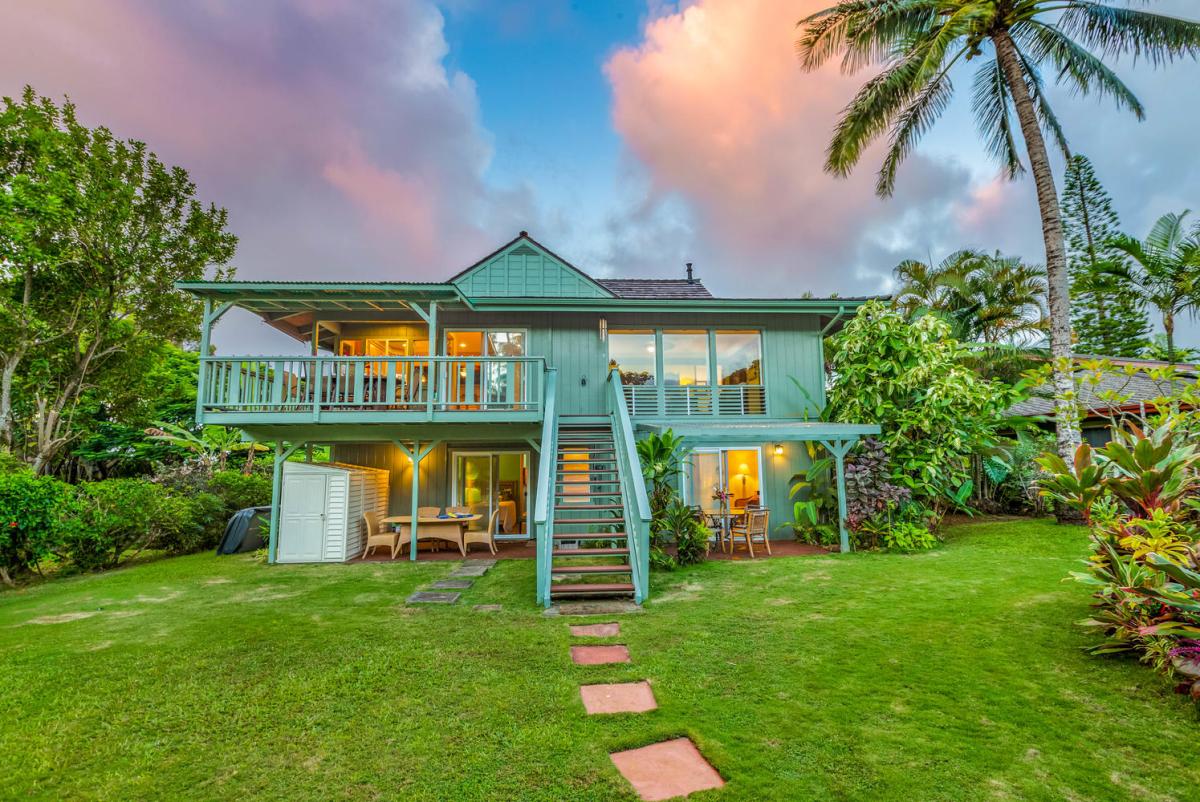 The home glows at dusk, welcoming you into a serene Kauai evening.