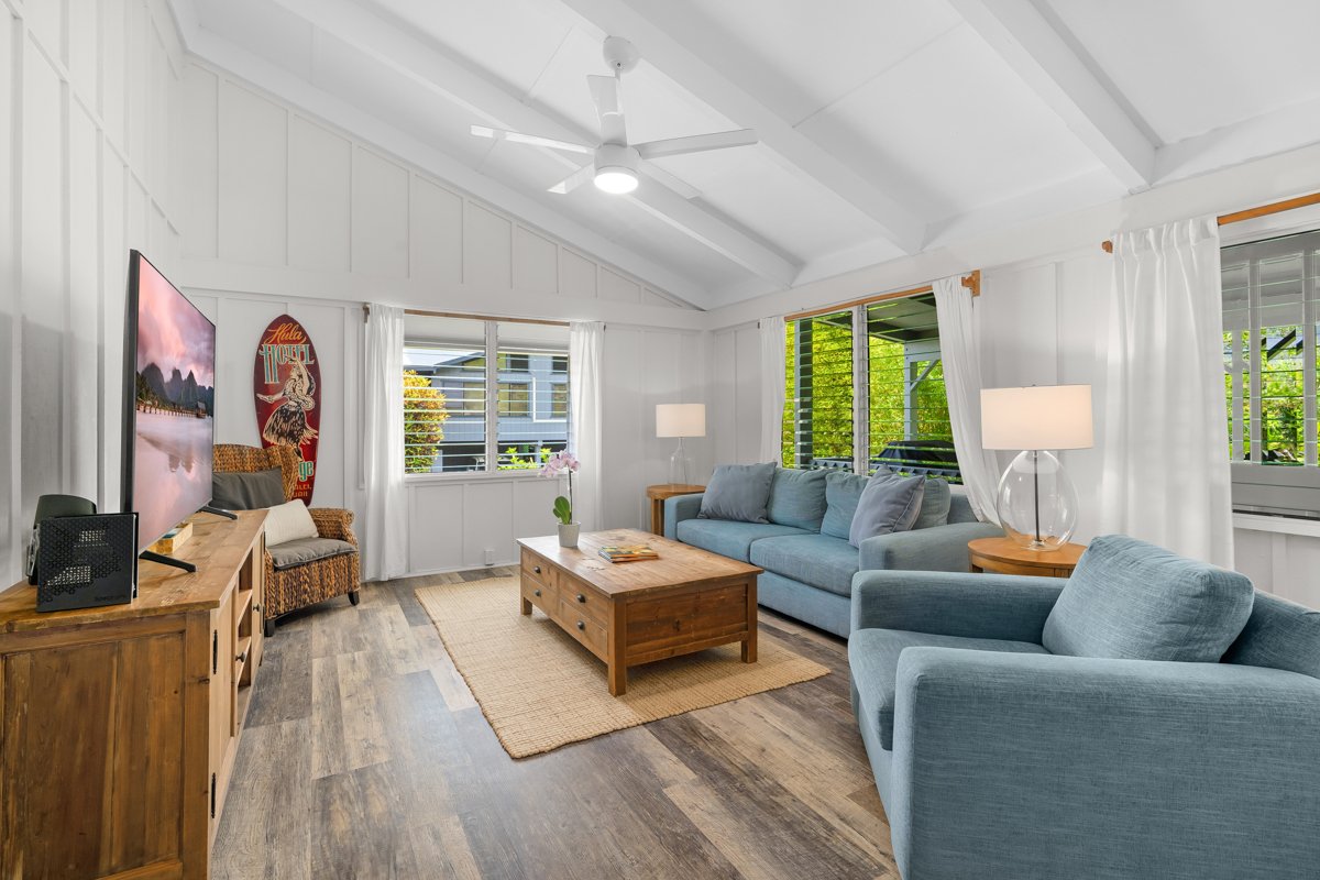The living room opens tall and bright, with a teal sofa built for the slow part of the afternoon.