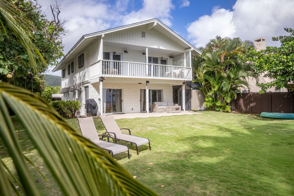 Charming view of the home from the backyard, with outdoor lounge chairs inviting guests to relax and enjoy sunny days.