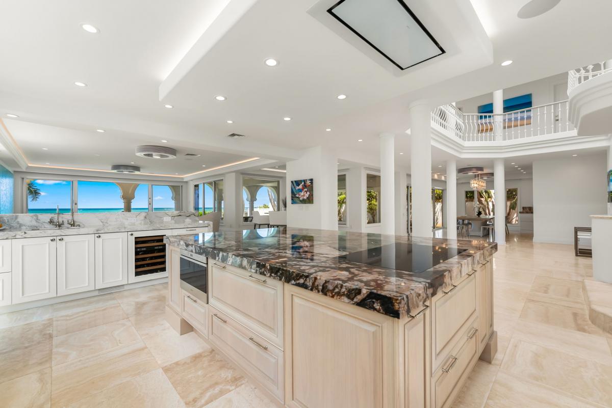 Designer kitchen blending modern finishes with warm wood tones, set against panoramic windows.