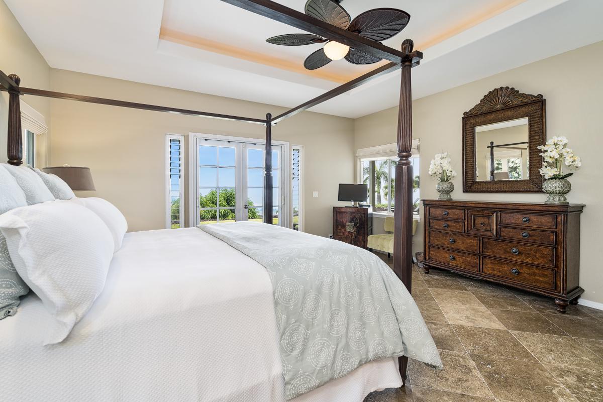 Enjoy soft linens, natural light, and A/C comfort in this peaceful primary bedroom with island flair.