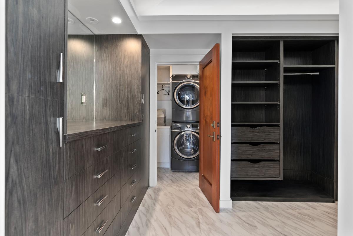Dedicated laundry room with full-size washer/dryer, storage cabinets, and exterior access for easy beach transitions.