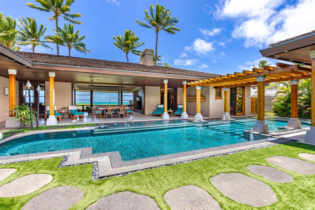 Poolside view framed by palm trees and stone path.