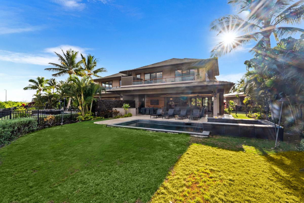 Backyard view showcasing the wide green lawn and sunny setting at Laule'a #13.