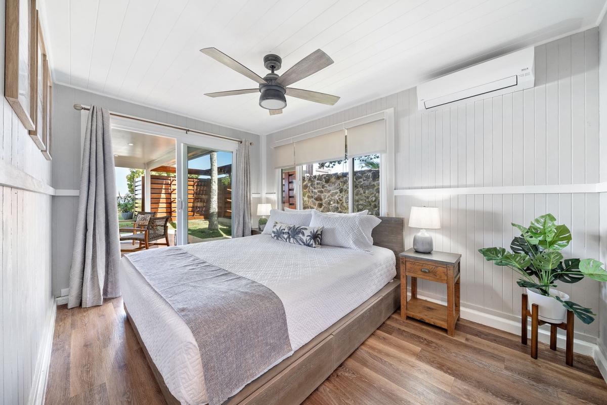 Natural light and coastal charm greet you in the lower-level primary suite with ceiling fan and sliding doors.