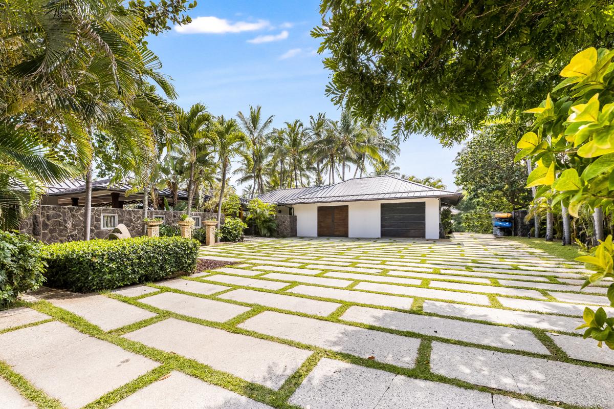 Ample driveway and guest parking surrounded by manicured palm-lined grounds.