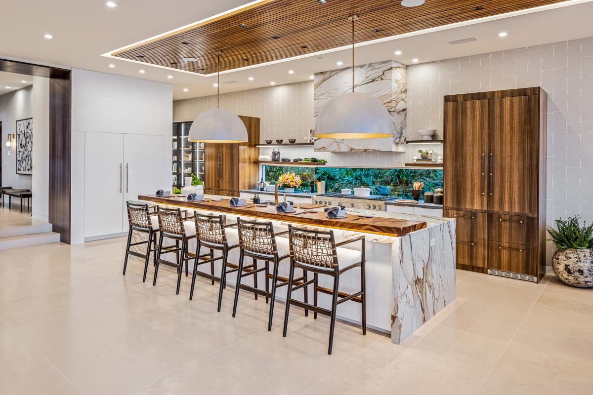 Prepare meals together in the gourmet kitchen, featuring marble counters, high-end appliances, and a spacious island with bar seating.
