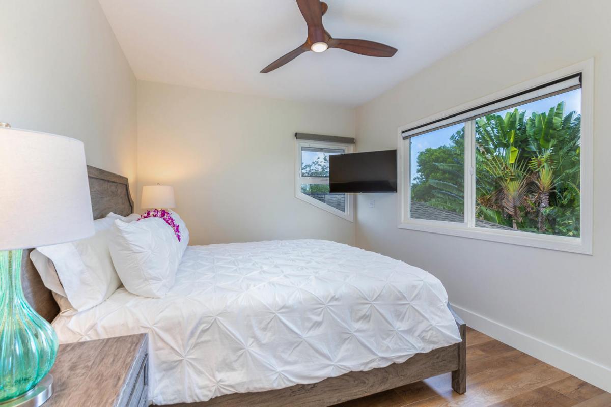 Guest bedroom at Pohaku Villa, complete with flat-screen TV and bright window views.