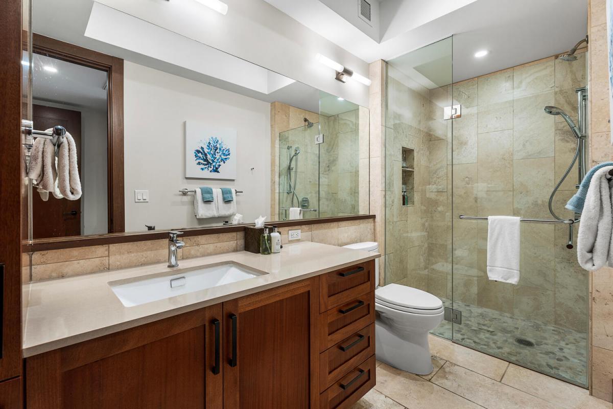 Stylish guest bathroom with walk-in shower and warm wood cabinetry.