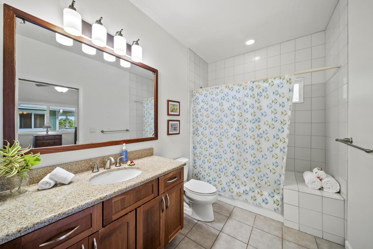 Private ensuite bathroom with shower/tub combo, granite vanity, and fresh design—adding convenience and comfort to this guest-friendly space.