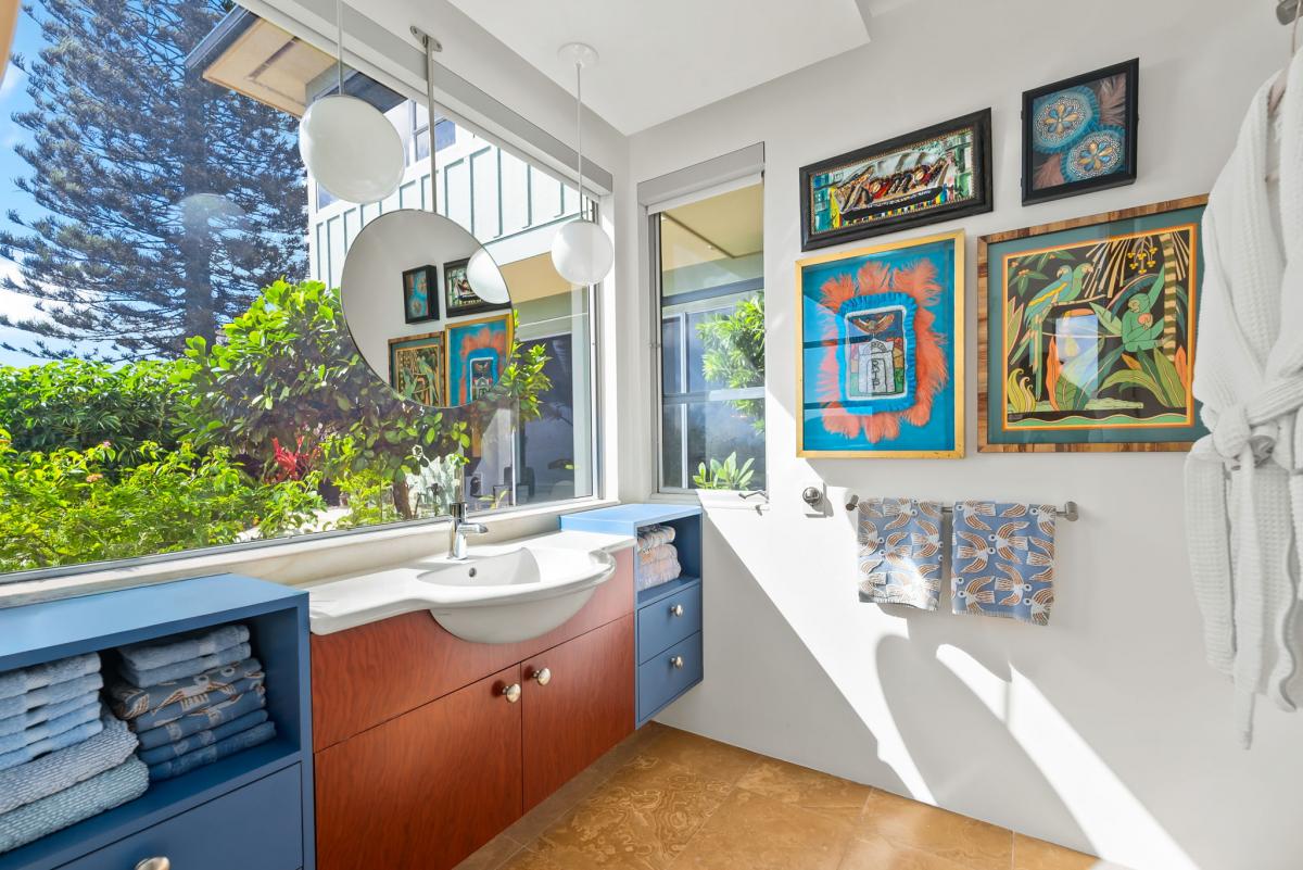 Art-filled vanity bathroom with plenty of sunlight and bold custom cabinetry.